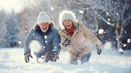 Elderly man and woman having a snowball fight and laughing, elderly people, winter trip, blurred background