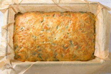 Freshly baked pie with spinach, sorrel and cheese in a baking dish with parchment, top view. Cooking step, step by step