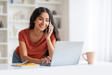 Energetic Millennial Eastern Woman Balancing Calls and Laptop Work