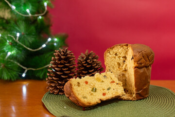 Panettone, Italian sweet bread with dried fruits, on blurred red Christmas background