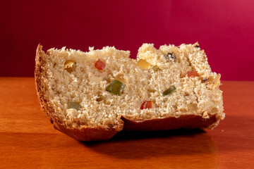 slice of panettone, Italian sweet, on wooden table and red background