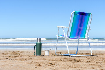 A mate and a thermos on the beach in front of the sea.