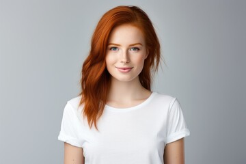 Obraz premium Smiling Portrait of a Beautiful Fictional Redhead Woman Wearing Blank White T-Shirt. Isolated on a Plain Gray Colored Background. Generative AI. 