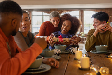 Friend giving a Christmas gift during a celebratory meal together