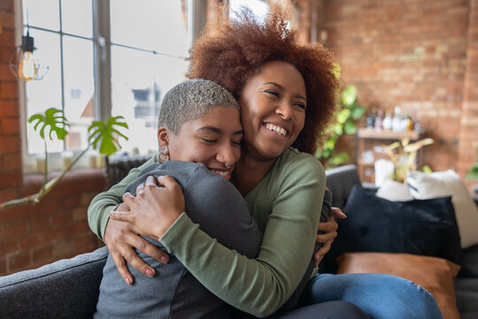 Female friends hugging on the sofa in a loft apartment