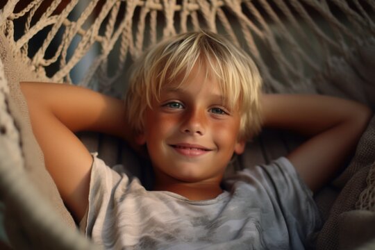 A young boy is pictured laying in a hammock with a joyful smile. This image can be used to depict relaxation, happiness, or enjoying outdoor activities.