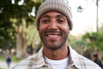 Portrait of multiethnic young man smiling and looking at camera. Friendly happy African American male person outdoors. Close up. - obrazy, fototapety, plakaty