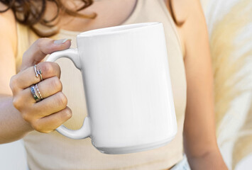 Fototapeta na wymiar Girl is holding white mug in hands. Blank 15 oz ceramic cup 