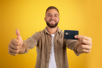 Glad millennial european guy show credit card and thumb up