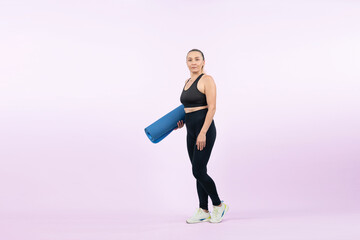 Fototapeta na wymiar Full body length shot athletic and sporty senior woman holding fitness exercising mat on isolated background. Healthy active physique and body care lifestyle after retirement. Clout