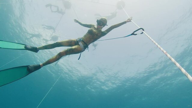 Freediving on the rope in a sea. Female freediver hangs on the rope and trains static breath hold during her warm up dive