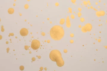 Tuinposter Gold glitter Ink watercolor drop blot on beige paper texture background. © Liliia