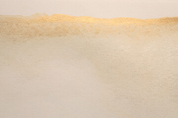Gold glitter Ink watercolor grain blot on beige paper texture background.