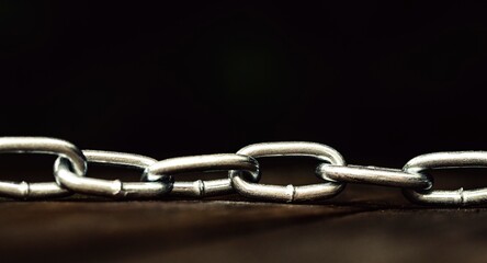 Obraz premium Metal shiny chain on a wooden surface close-up