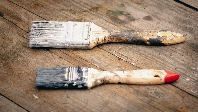 Brush covered with paint on a wooden background