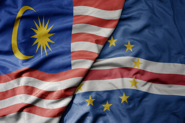 big waving realistic national colorful flag of malaysia and national flag of cape verde .