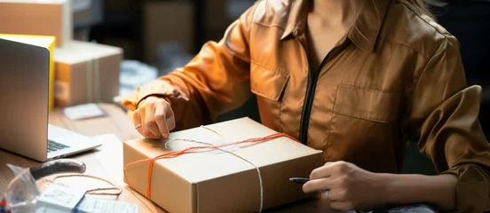 Foto op Canvas A close up as a woman meticulously prepares a shipment with utmost care © shaista