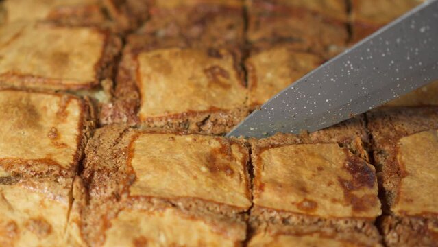 Cutting pie prepared at home with knife into portions, close-up, slight camera movement.
