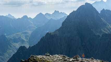 Tatry Wysokie, Rysy, zejście ze szczytu po stronie Słowackiej, w piękny letni dzień. Turystka z pomarańczowym plecakiem - obrazy, fototapety, plakaty
