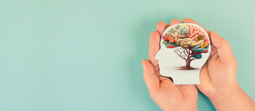 Hands holding paper head, human brain with flowers, self care and mental health concept, positive thinking, creative mind