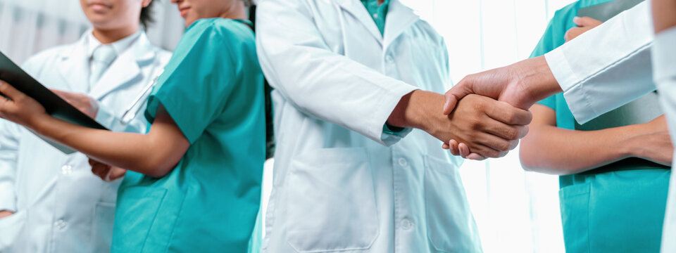 Group of medical staff doctor nurse and healthcare specialist profession handshaking in hospital. Medical teamwork and healthcare cooperation in panoramic banner background. Neoteric