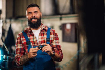 A portrait of a tattooed factory employee at work, holding a metal ring.