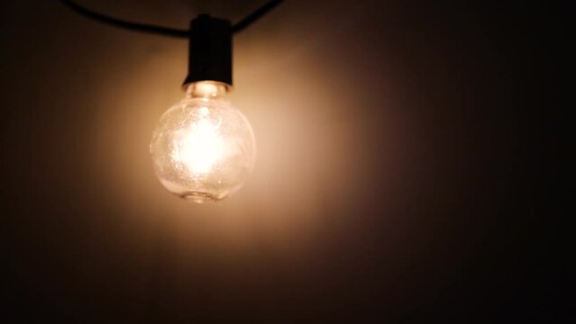 An old light bulb is turned off in a dark basement.