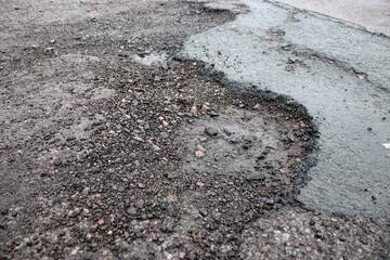 Crumbling deteriorated road surface taken after light rainfall