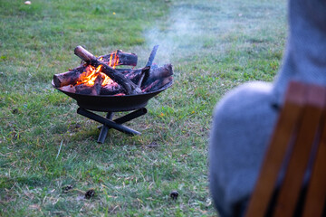 Metal fire bowl with burning wood in the yard. Safe decorative fire pit