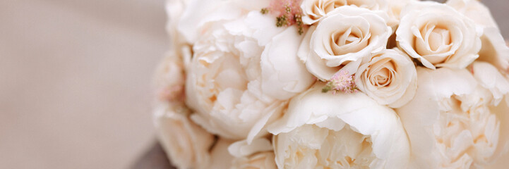 Wedding bouquet of white and beige roses lies on a granite slab. Banner with copy space.
