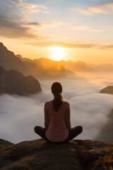Woman sitting yoga pose on a rock at sunrise in the morning