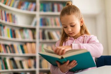 Fototapeta na wymiar Schoolgirl attentively leafing through a book