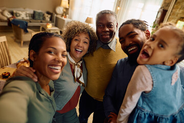Cheerful multiracial extended family taking selfie on Thanksgiving and looking at camera.