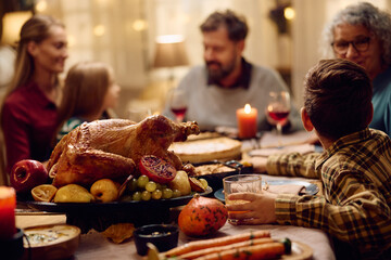 Thanksgiving turkey on dining table with extended family in background.