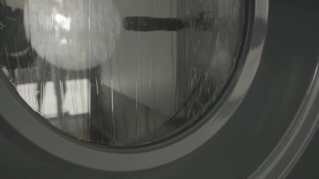 Lavadora de una tintorer&iacute;a con el cristal lleno de gotas de agua
