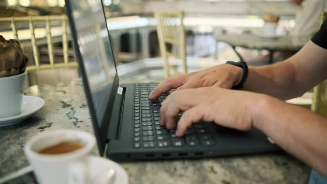 Emprendedor digital tecleando con su port&aacute;til en una cafeteria