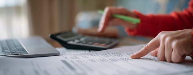 The hands of an elderly woman with a calculator and a lot of utility bills. Pensioner and payment of utilities for heating © Anna