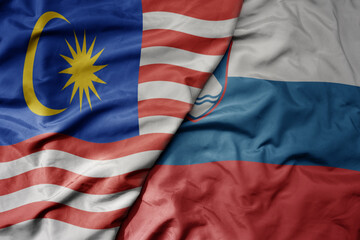 big waving realistic national colorful flag of malaysia and national flag of slovenia .