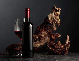 Red wine and old weathered snag on a black stone table.