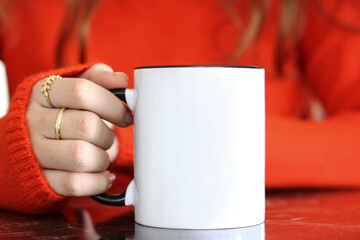 Girl is holding black handle white 11 oz mug in hands with orange sweater. Blank ceramic cup