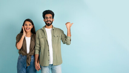 Excited multiethnic couple showing blank space for advertisement