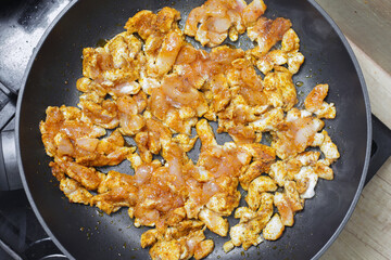 Making turkish doner kebab at home. Raw chicken pieces on frying pan. Marinated chicken in spices. Gyros dish recipe. Dinner frying background. Simple meat background. Closeup food texture.