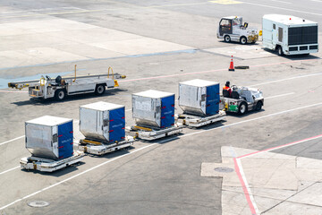 High angle view on tarmac or apron with service road on airport with baggage tractor-trailers...