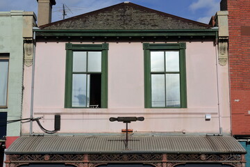 Pink rendered cement wall and pitched slate roof of Victorian commercial terrace on Brunswick...