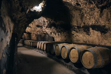 Row of wooden barrels bound with iron hoops in a bodega. Wine barrels made of oak at dark wine cellar. Wine cave at Beqaa valley, Lebanon