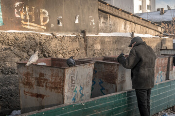 The poor homeless man searching for food in a dirty trash container in Ulan-Ude, Buryatia, Russia.
