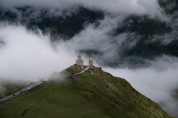 A view of the iconic Trinity Church in Stepantsminda surrounded by low clouds