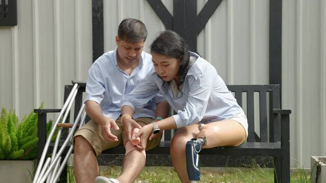 woman wearing prosthetic legs helps her husband injured in an accident using crutches.equality concept, disability, life difficulties
