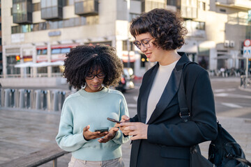 Two friends using smartphone in the street