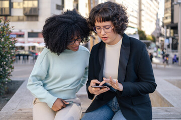 Two friends looking at smartphone in the street